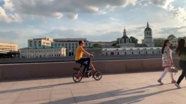 Moskova, Rusya - 29 Temmuz 2019: Adam sıcak bir yaz akşamı Moskova Nehri'nin setinin sokaklarında bir bisiklet Strida sürmek