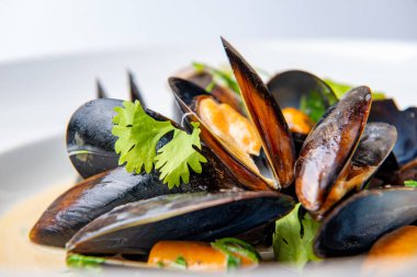 Soslu ve otlu beyaz tabakta harika midyeler.