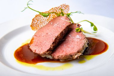 Beyaz tabakta servis edilen güzel pişmiş biftek eti.