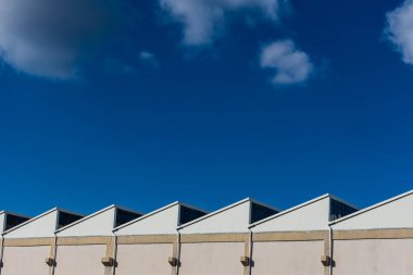 Fabrika çatıları görünümünü güneşli mavi backgroung üzerinde