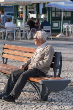 Portimao, Portekiz: 20 Mayıs 2018 - yalnız bir şehir olarak bankta oturan yaşlı adam.