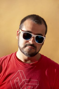 adam kırmızı gömlek ve sarı bir arka plan üzerinde beyaz güneş gözlüğü.