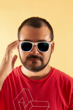 adam kırmızı gömlek ve sarı bir arka plan üzerinde beyaz güneş gözlüğü.