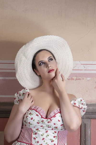 View of a countryside young lady woman with white dress and red flowers and hat on a abandoned palace with old mural paintings.