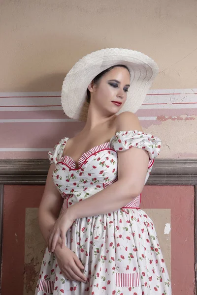 View of a countryside young lady woman with white dress and red flowers and hat on a abandoned palace with old mural paintings.