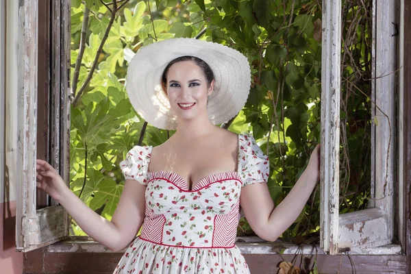 イチジクの木の枝に対して放棄された宮殿で白いドレスと赤い花と帽子の田舎の若い女性の女性観 — ストック写真