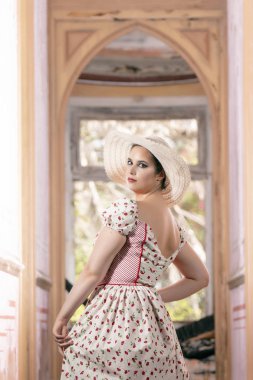 Beyaz elbise ve kırmızı çiçekler ve şapka ile bir contryside genç bayan kadın görünümünü üzerinde terk edilmiş bir saray.