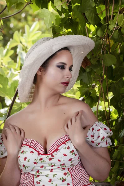 一个农村年轻女士的视图白色的礼服和红色的花朵和帽子在废弃的宫殿对无花果树枝 — 图库照片