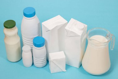 Süt şişelerini ve mavi bir arka plan üzerinde izole paket karışımı.