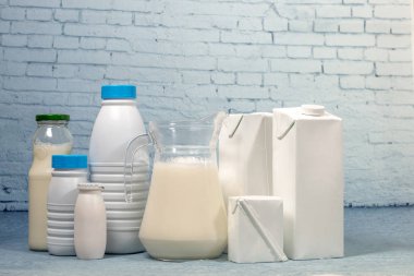 Süt şişelerini ve mavi tuğla arka plan üzerinde izole paket karışımı.