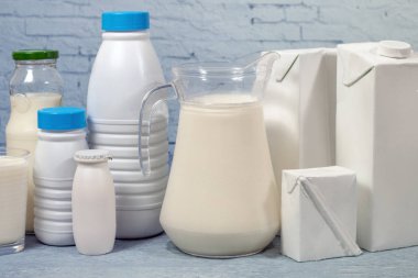 Süt şişelerini ve mavi tuğla arka plan üzerinde izole paket karışımı.