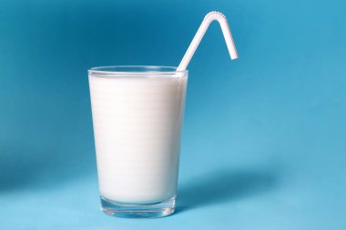 tam bir bardak süt ile mavi bir arka plan üzerinde izole saman.