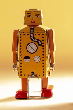 Sarı bir arka plan üzerinde yalıtılmış bağbozumu Teneke robot oyuncak.