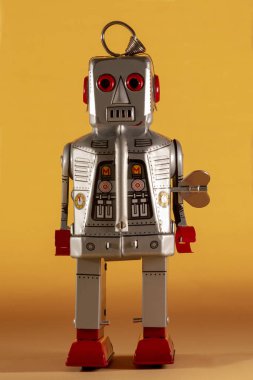 Sarı bir arka plan üzerinde yalıtılmış bağbozumu Teneke robot oyuncak.