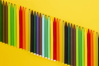 sarı bir arka plan üzerinde izole keçeli kalem kümesi.