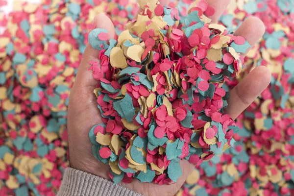 Hand grabs a mix of colorful confetti.
