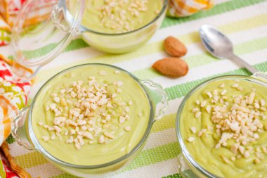 Taze ve tatlı avokado armut kremalı tatlı ve cam kaselerin üzerinde küçük badem parçaları..