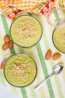 Taze ve tatlı avokado armut kremalı tatlı ve cam kaselerin üzerinde küçük badem parçaları..