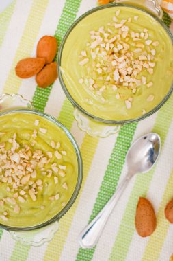 Taze ve tatlı avokado armut kremalı tatlı ve cam kaselerin üzerinde küçük badem parçaları..