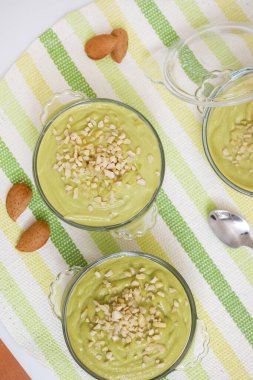 Taze ve tatlı avokado armut kremalı tatlı ve cam kaselerin üzerinde küçük badem parçaları..