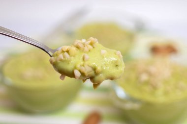 Taze ve tatlı avokado armut kremalı tatlı ve cam kaselerin üzerinde küçük badem parçaları..