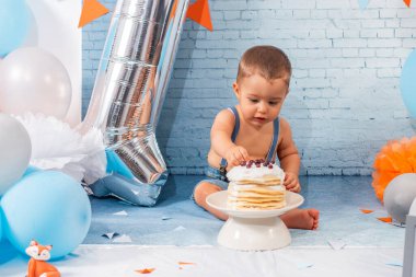 Balonlardan, kurdelelerden, tuğla duvar kâğıdından ve kreplerden oluşan bir seti olan bir yıllık erkek bebek için parti..