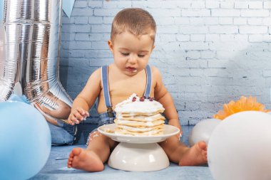 Balonlardan, kurdelelerden, tuğla duvar kâğıdından ve kreplerden oluşan bir seti olan bir yıllık erkek bebek için parti..