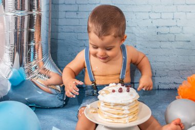 Balonlardan, kurdelelerden, tuğla duvar kâğıdından ve kreplerden oluşan bir seti olan bir yıllık erkek bebek için parti..