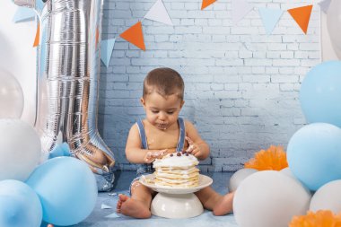 Balonlardan, kurdelelerden, tuğla duvar kâğıdından ve kreplerden oluşan bir seti olan bir yıllık erkek bebek için parti..