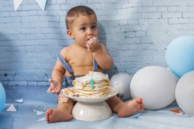 Balonlardan, kurdelelerden, tuğla duvar kâğıdından ve kreplerden oluşan bir seti olan bir yıllık erkek bebek için parti..