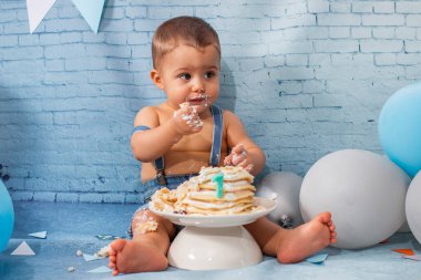 Balonlardan, kurdelelerden, tuğla duvar kâğıdından ve kreplerden oluşan bir seti olan bir yıllık erkek bebek için parti..