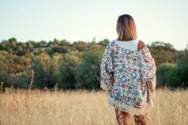 Kırsalda poz veren güzel bir kız kuru çimlerin üzerinde kısa kot pantolonla.