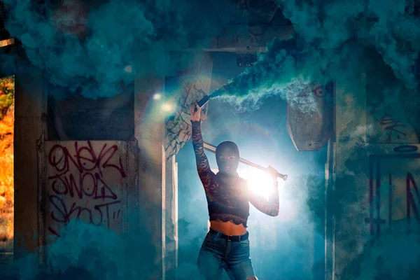 用烟雾弹在废弃的工厂里拿着球棒和巴拉克拉瓦的危险女孩 — 图库照片