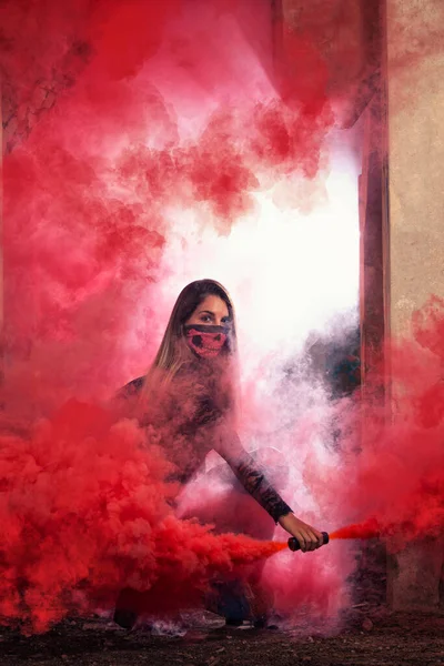 一个带着粉色口罩的危险女孩在一个废弃的工厂里用烟雾弹 — 图库照片