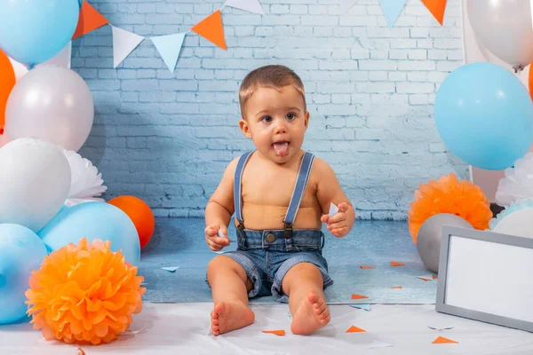Party for one year baby boy with a set composed of balloons, ribbons, and brick wall paper.