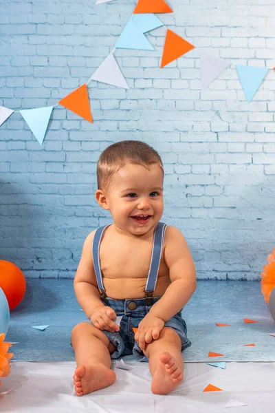 Party for one year baby boy with a set composed of balloons, ribbons, and brick wall paper.