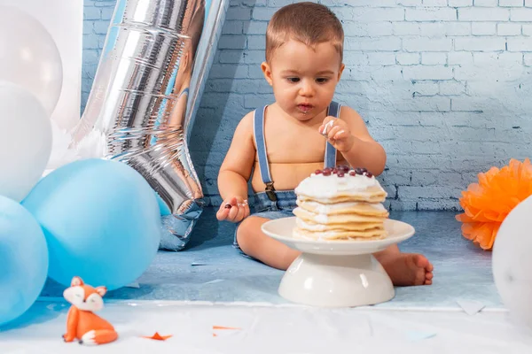 Party for one year baby boy with a set composed of balloons, ribbons, and brick wall paper and pancakes.