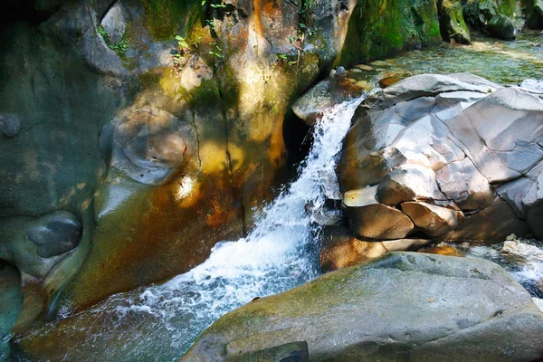 Small fair waterfall among the rocks in a mountain forest