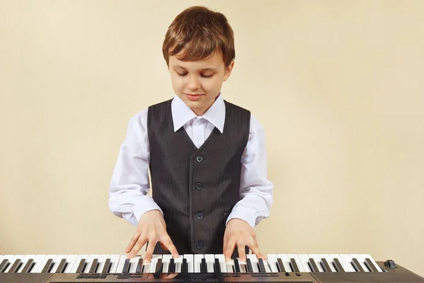 Little cut boy play the keys of the electronic piano