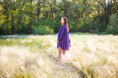 Hamile genç kız günbatımında ışık elbisesini parkta yürüyüş
