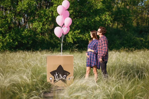 Terhes felesége élt férjével egy séta a parkban van, őket labdák és corton doboz — Stock Fotó