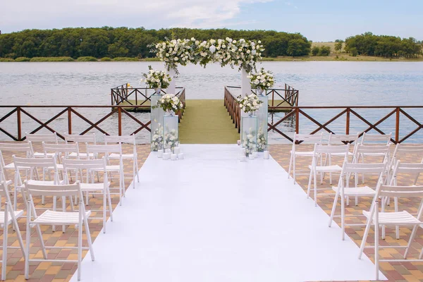 Γάμου. Τελετή. Γάμος αψίδα. Αψίδα γάμου κατασκευασμένα από κλαδιά, λουλούδια και την πρασινάδα είναι στο πράσινο γρασίδι στην όχθη του ποταμού — Φωτογραφία Αρχείου