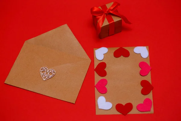 Valentines Day, 14 Februari - sebuah amplop dengan hati merah dan lembaran untuk catatan dengan latar belakang merah, hadiah yang diikat dengan pita merah, sebuah konsep liburan — Stok Foto