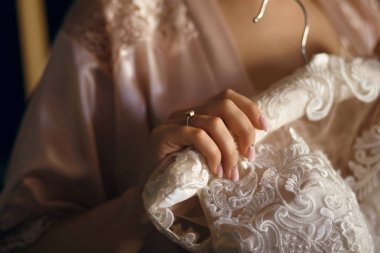 gelin beyaz bir elbise onun elinde tutan, onu parmağına alyans bir askı elbise asmak olduğunu