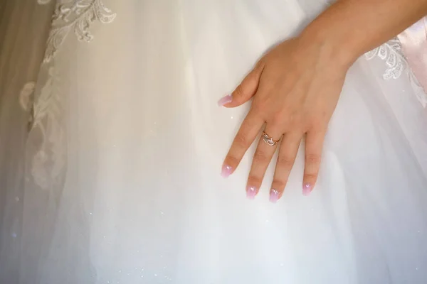 Foto der Hand der Braut mit einem Ehering auf dem Hintergrund eines weißen Kleides — Stockfoto