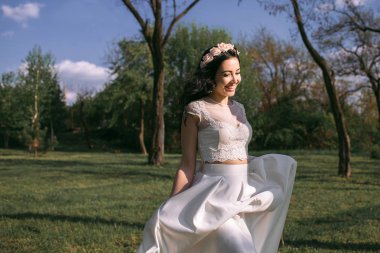 Güzel beyaz bir elbise içinde muhteşem şık siyah saçlı gelin parkta yürüyor. Kız çalışır ve saçları rüzgarda geliştirir