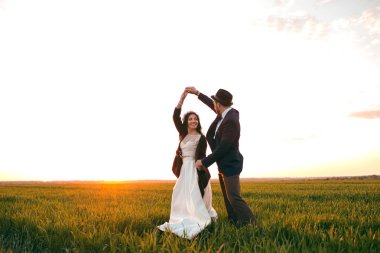 Düğün gününde, gün batımı, şık bir damat ve güzel bir gelin dans genç bir çift bir dans poz gelin damat holding gelin düğün Gelenekselyıllık damat üzerinde dans poz tutar