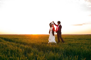 Gelin Damat Düğün gününde, gün batımı, şık bir damat ve güzel bir gelin dans genç bir çift bir dans poz tutar.