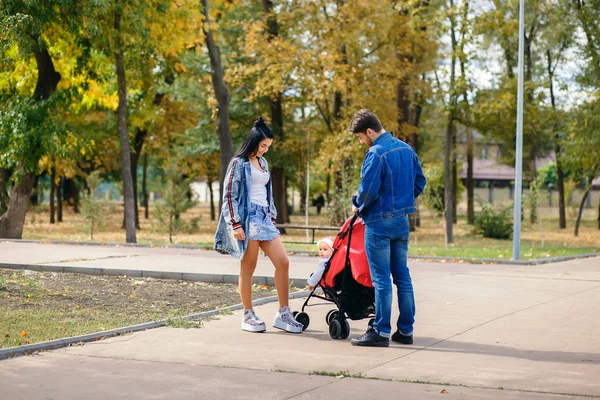 Annem ve babam parkta kızları bir bebek arabası, güzel bir güneşli gün, güzel bir aile ile yürüyor