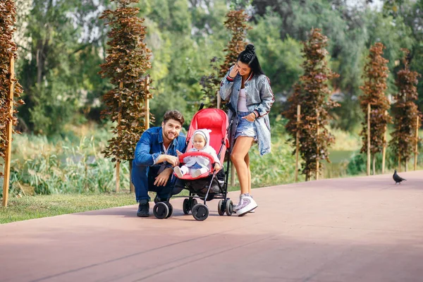 Annem ve babam parkta kızları bir bebek arabası, güzel bir güneşli gün, güzel bir aile ile yürüyor